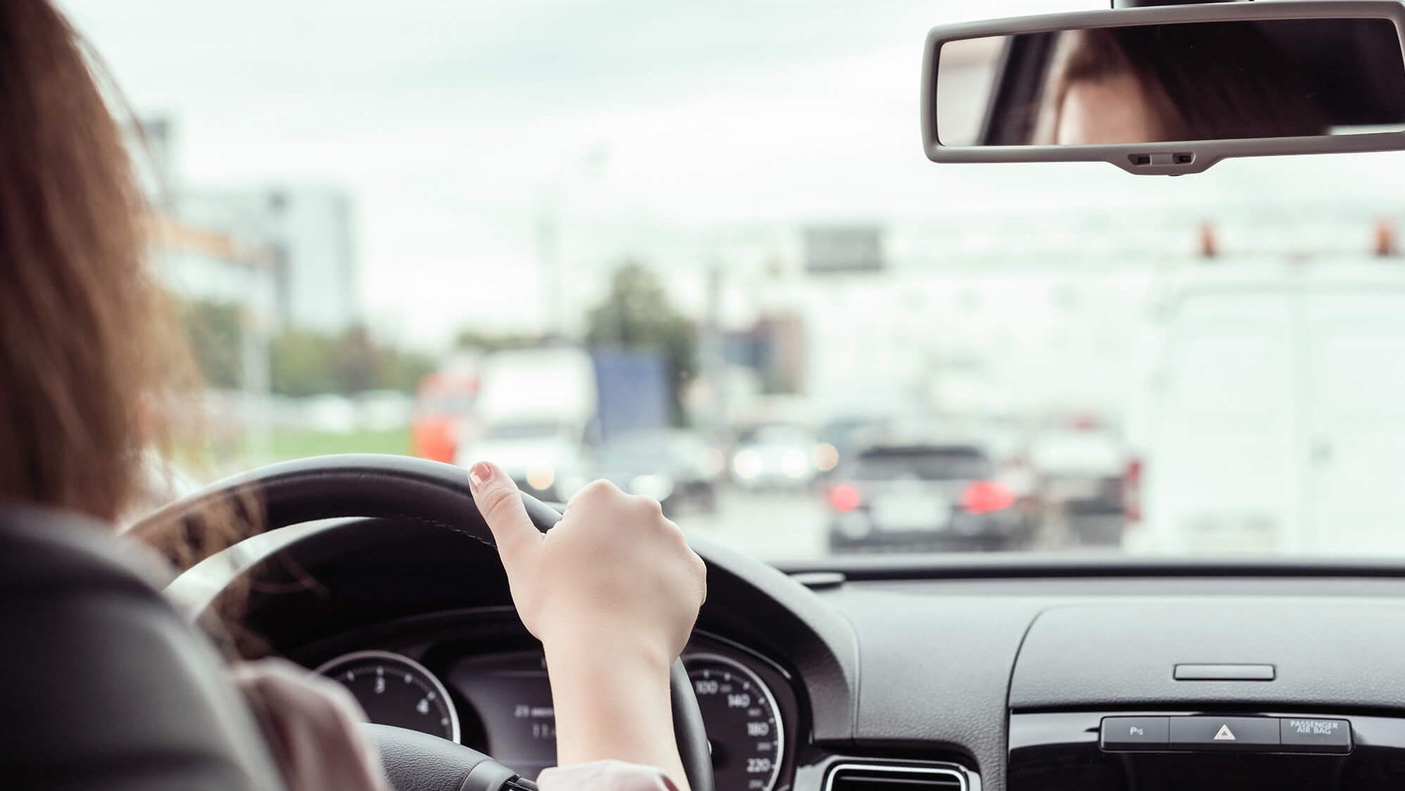 A woman is driving on a busy street with traffic.